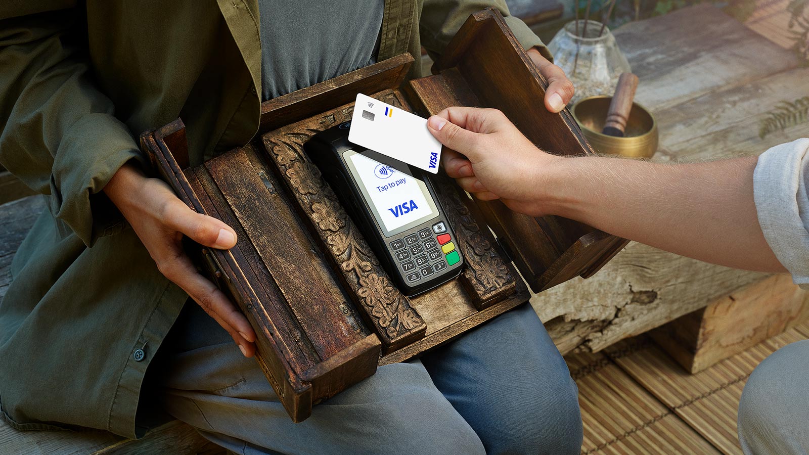 person paying with their card on terminal on a wooden tray